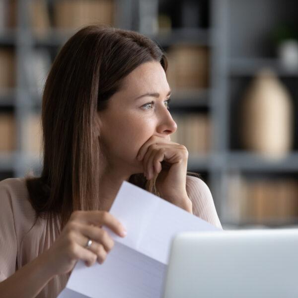 an image of a woman reading through documents and contemplating. This is the feature image for the guide to understanding corporate insolvency.