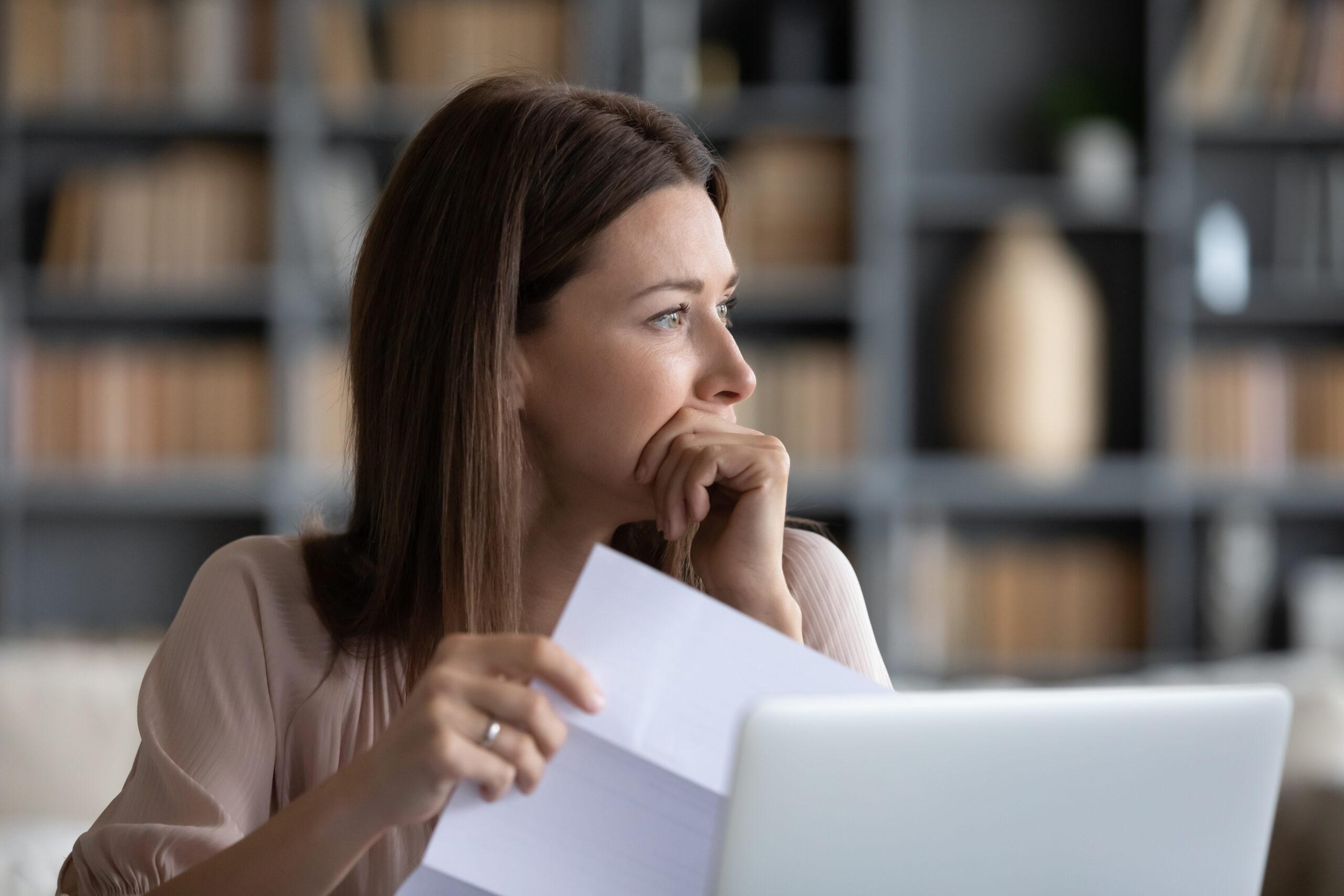 an image of a woman reading through documents and contemplating. This is the feature image for the guide to understanding corporate insolvency.